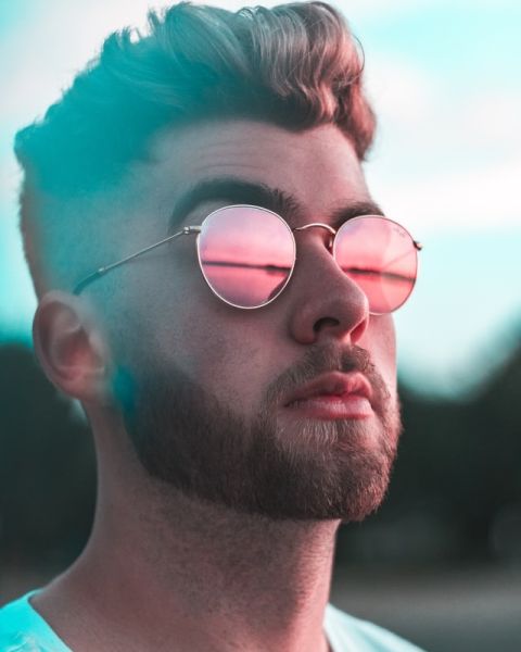 Portrait eines jungen Mannes mit Bart und bunter Sonnenbrille
